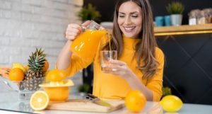 Happy woman pouring orange juice into a glass